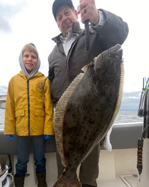 Father and son holding a large halibut catch together