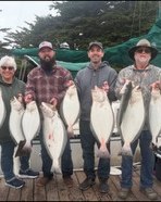 Group of six anglers holding their halibut catch on the dock