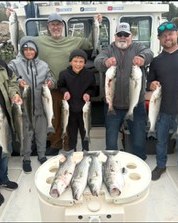 Family group holding striped bass catches on the boat